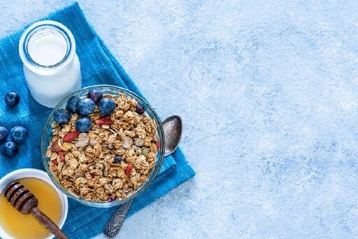 Tazón con granola, fruta, leche y miel en desayuno continental 