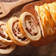 Pancitos de jamón, preparación propia de la panadería latina. Pancitos de jamón tajado en cuatro pesados sobre tabla de picar.