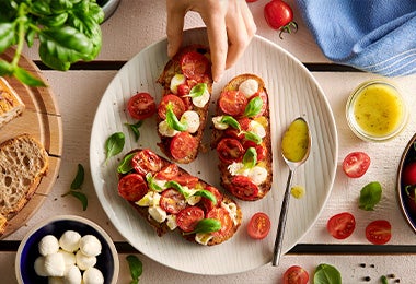  Ensalada caprese con aceite de oliva y un par de hojas de albahaca en toma cenital.