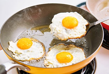 Fritando huevos en una sartén con las precauciones necesarias para evitar una quemadura por aceite