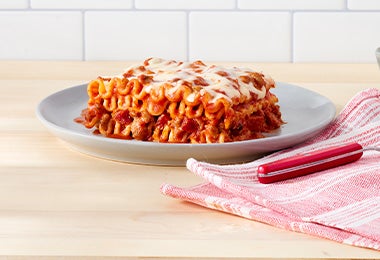 Plato con lasaña y grisines para acompañar