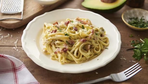 Pasta carbonara con pollo, tocino y hierbas en un plato hondo